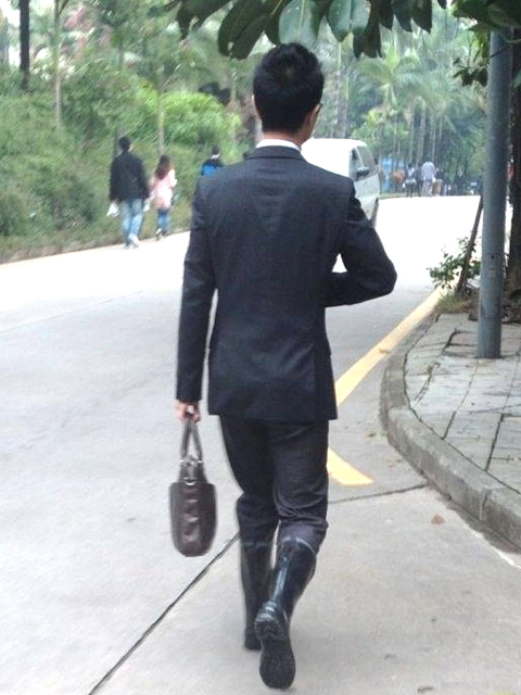 young guy suited and rubber booted (apparently, the road is dry when he goes off the work). 