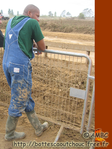 Black guy in muddy bib & braces &  boots. Gummistiefel, stivali di gomma, 2005.