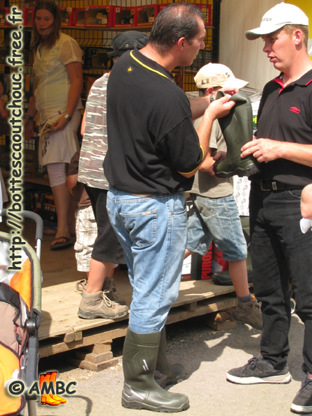 A salesman from Dunlop showing his wellies for sale to a young guy. Gummistiefel, botas de goma, bottes en caoutchouc, rubber laarzen, Libramont, Belgium 2008.