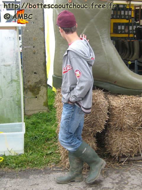 Young guy in wellies touching the huge Boot.  Gummistiefel, botas de goma, bottes en caoutchouc, rubber laarzen, 2007.