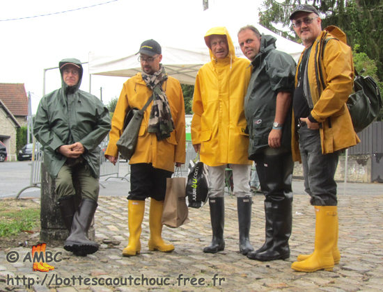5 Rubberbooted fans wearing PVC raincoats &  wellies in Rubelles streets; France,  Sept. 2011. (Flea-market)